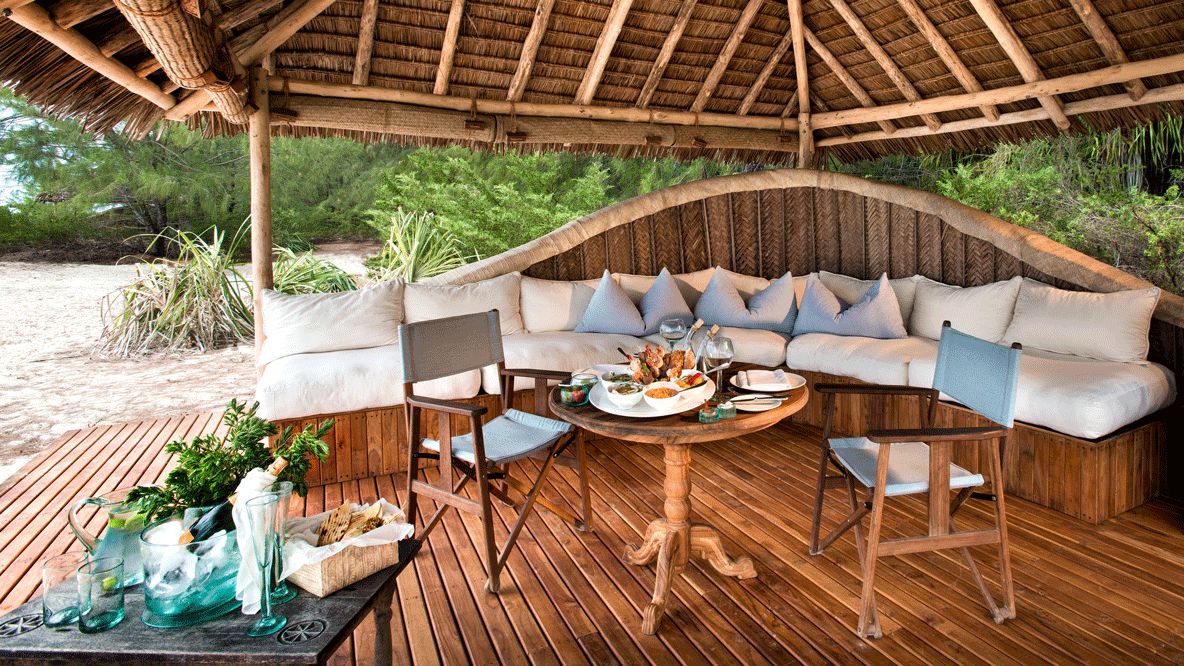 hotels in heaven andBeyond mnemba island lodge culinary breakfast food sparkling wine pillow seats chair couch wine glass napkin dishes table plants sand
